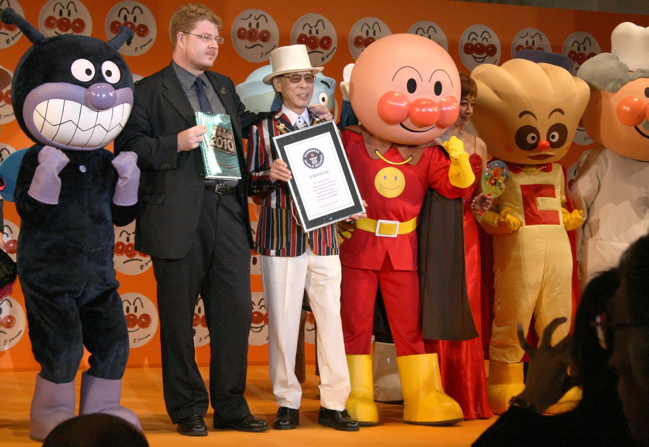 90歳(卒寿)を祝うパーティーでの漫画家のやなせたかしさん(中央)。『アンパンマン』のキャラクター数が、単独のアニメーション作品内では世界一と認定するギネスブック証明書を手にした=2009年7月、東京都内のホテル(時事)