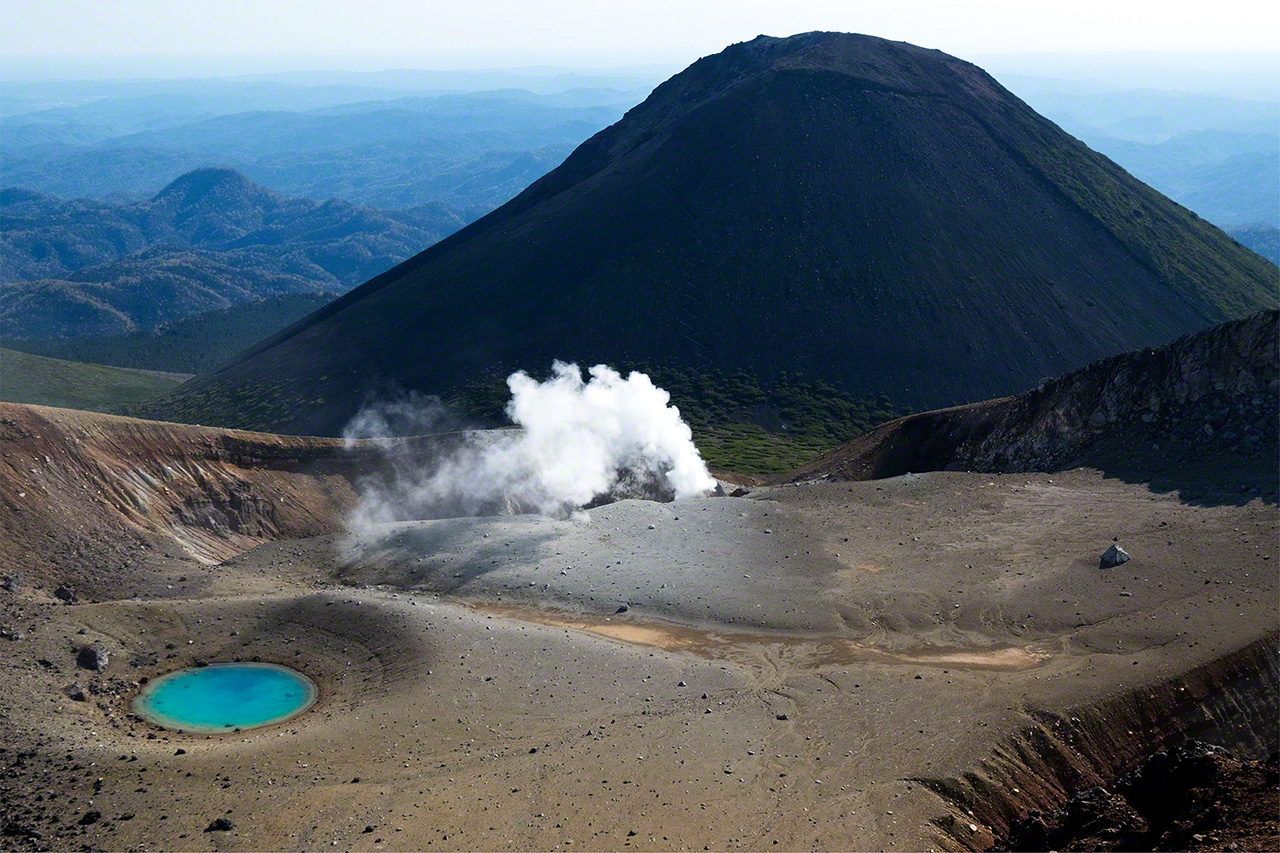 仍有火山活动的雌阿寒岳上的青沼和耸立于背后的阿寒富士（1476米）  