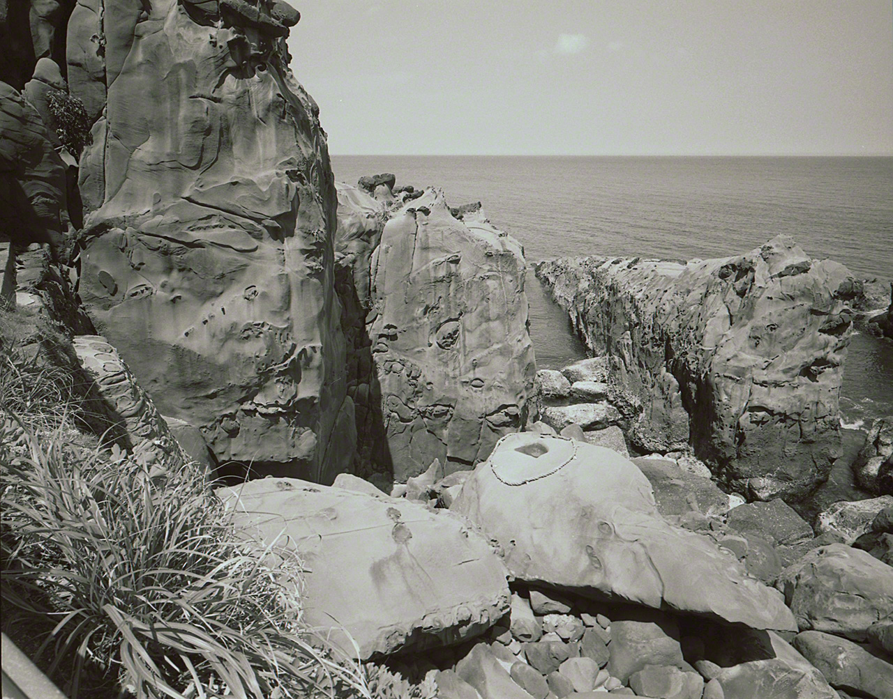 The strange-shaped rocks and boulders in front of the honden. In the center is the “turtle rock,” marked off by the shimenawa rope as a sacred spot. (© Ōsaka Hiroshi)