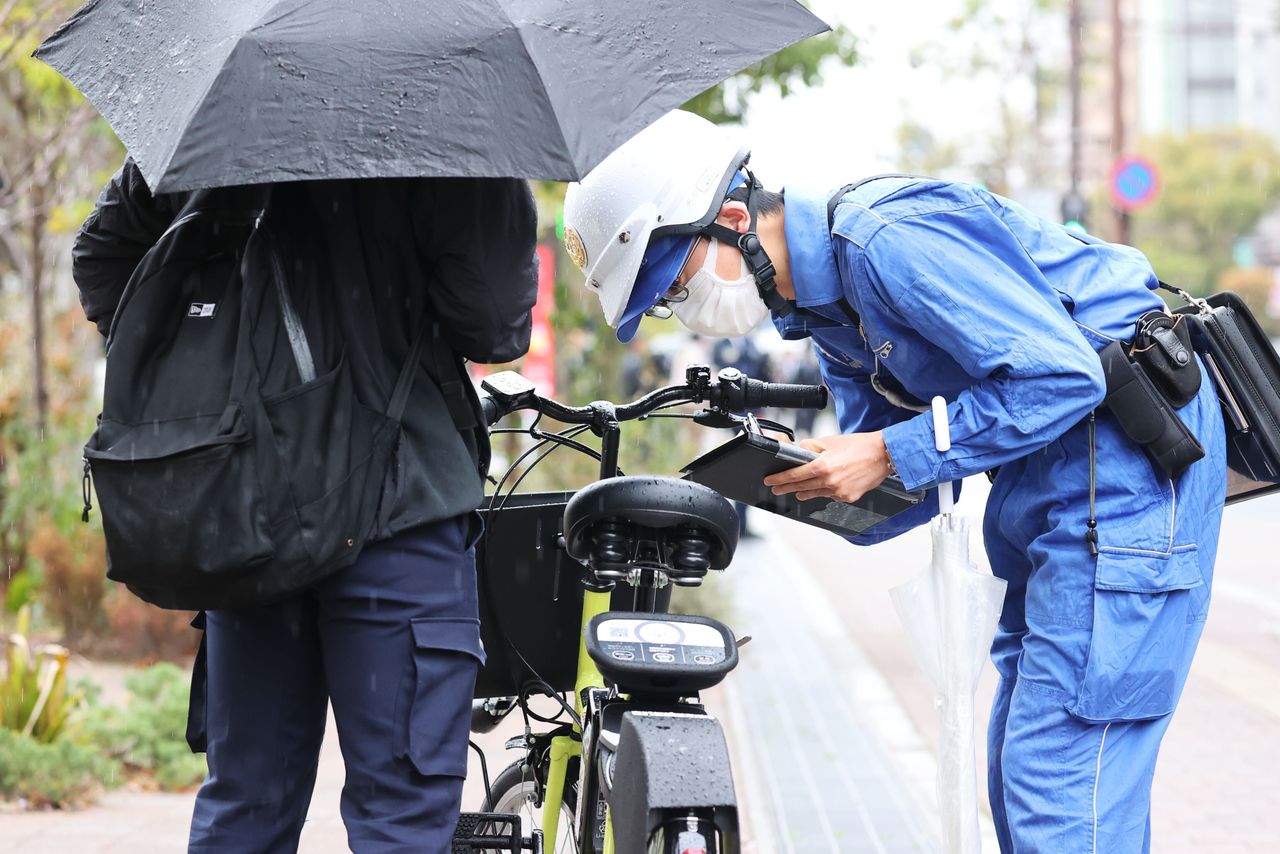 A police officer in Okayama stops a cyclist for holding an umbrella on April 1, 2026. (©︎ San’yō Shimbun/Kyōdō)