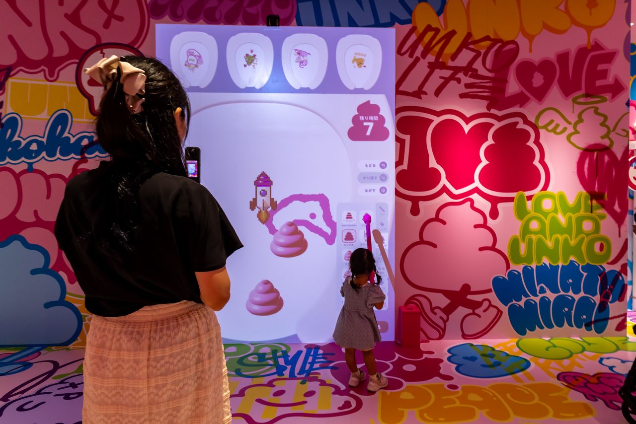 The “U.G.A.” (Unko Graffiti Art) photo spot and “Let’s Draw Your Poop,” where visitors doodle on a digital toilet canvas. (© Nippon.com)
