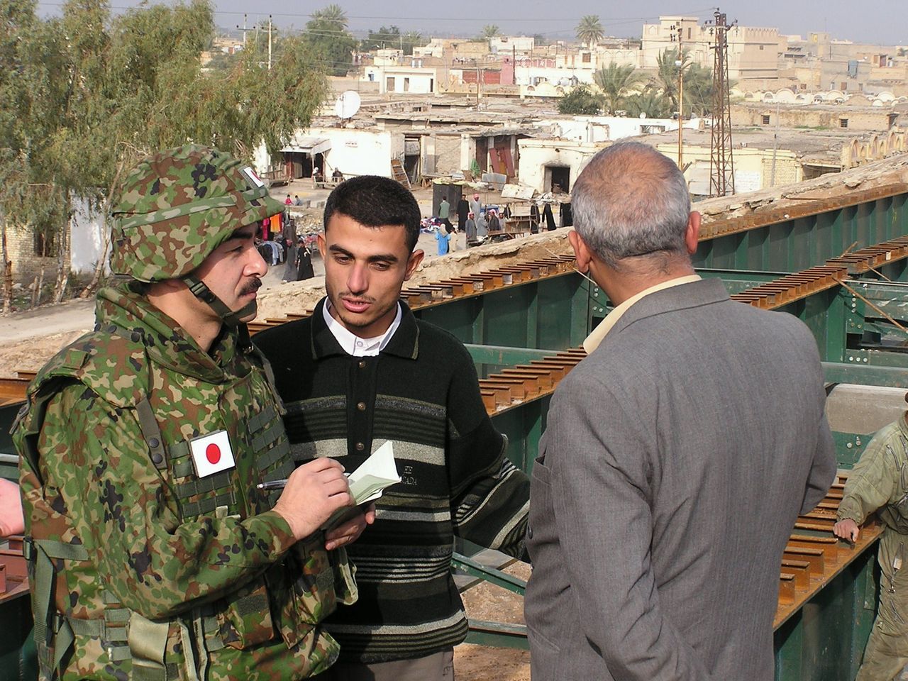 GSDF Colonel Satō Masahisa, commander of the Japanese reconstruction mission in Iraq, speaks to local officials about conditions at a bridge near Samawah on January 26, 2004. (© Jiji)