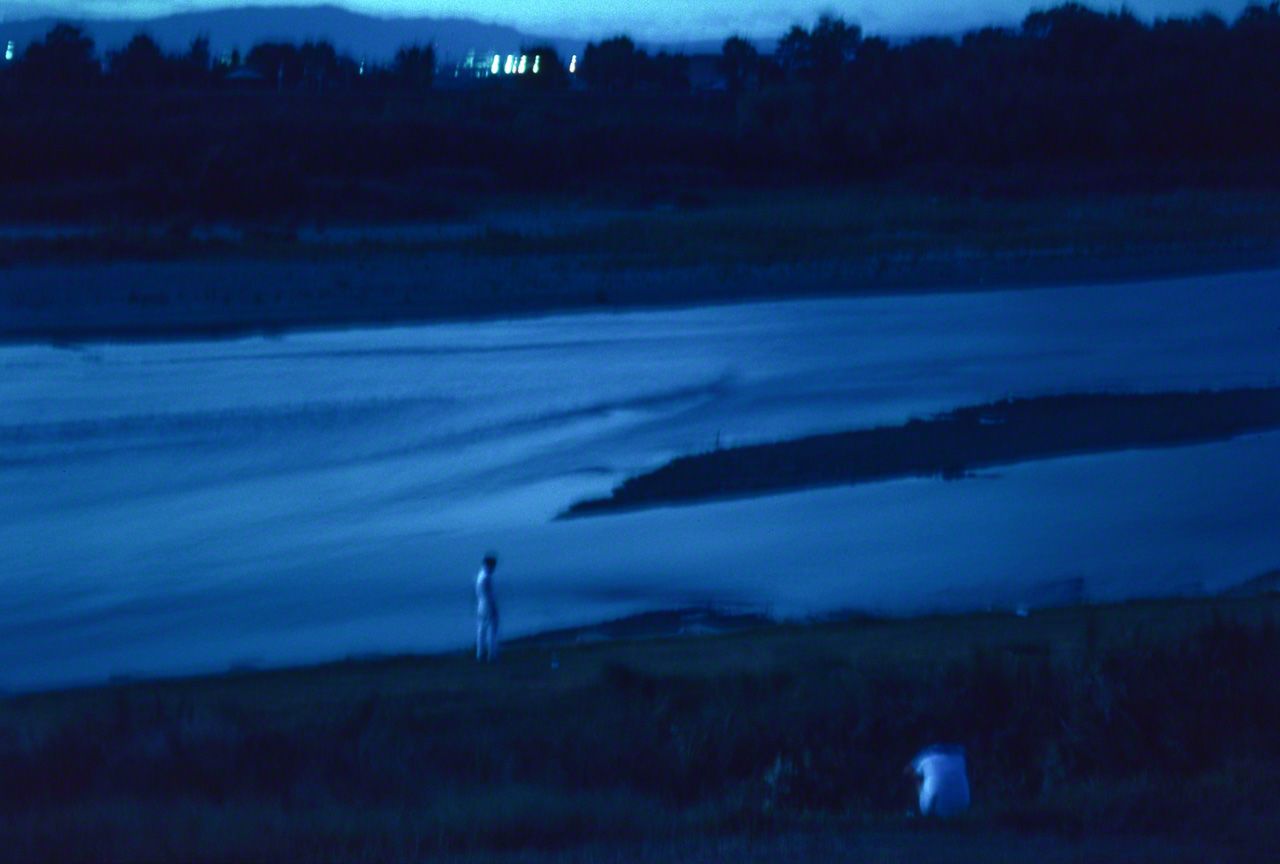 In Japanese Buddhism, the souls of the dead cross the Sanzu-no-Kawa to get to the afterlife. The eerie glow of this photograph was achieved by using a long exposure at dusk, at the Yahagi River in Aichi Prefecture. (© Ōnishi Naruaki)