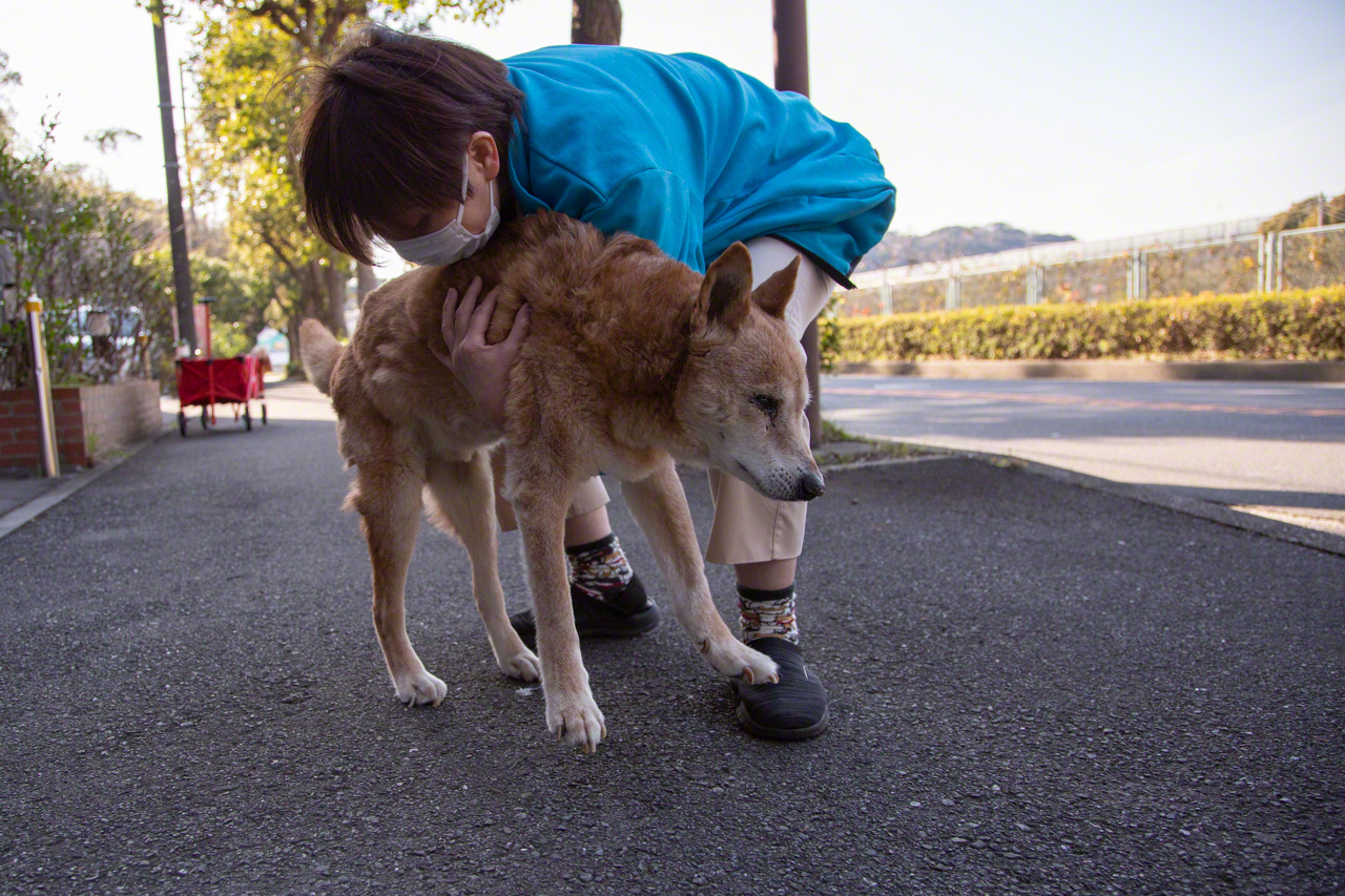 Daiki loves to feel the breeze on his back. With a helping hand from his caregiver, he summons his last reserves of strength and steadies himself to start walking. (© Ōnishi Naruaki)