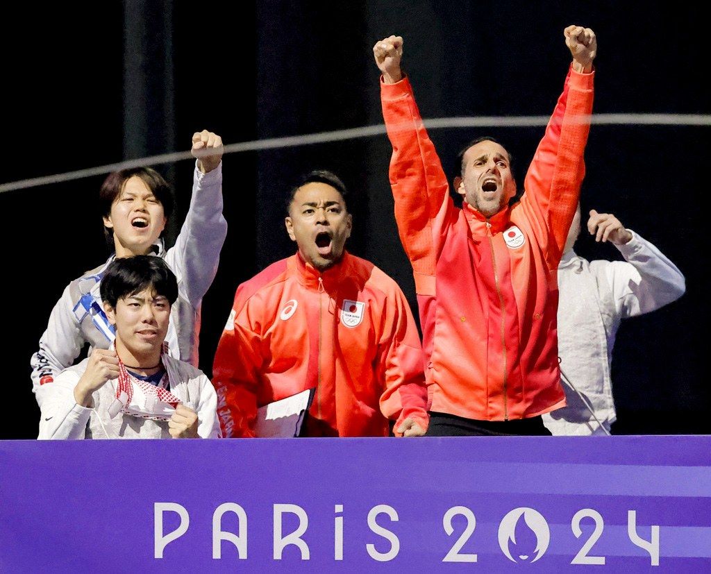 2024年8月5日にフランスのパリで行われた男子サーブル決勝での日本の劇的な勝利を祝って腕をあげるエルワン・ル・ピショーさん（右）。 (©共同通信社)