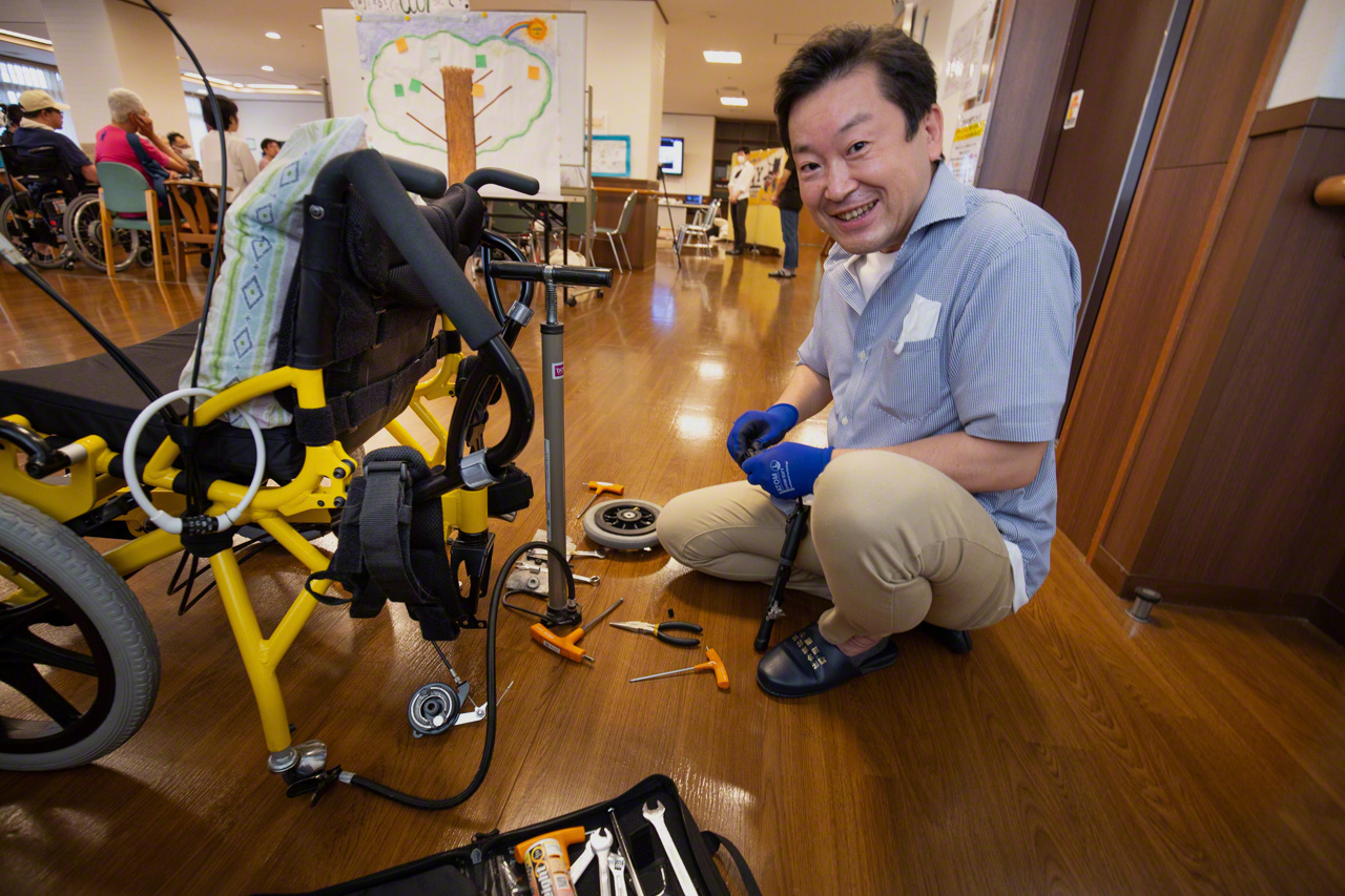 Tess Co. President Suzuki Kenji travels all over Japan attending test-driving events, where he can often be seen squatting beside a wheelchair with his toolbox open. He says that ideas for improvements often come from tinkering with the mechanism. (© Ōnishi Naruaki)