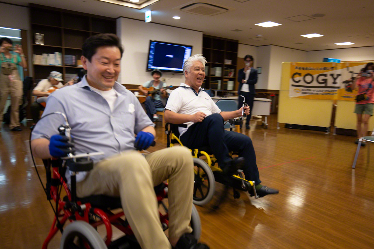 Suzuki and Tomono (right) entertain event participants with a friendly Cogy race. (© Ōnishi Naruaki)