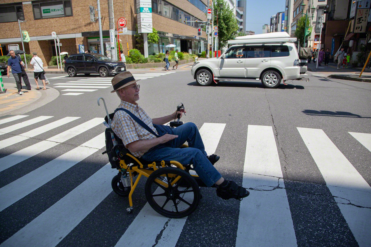 A Cogy user cruises around town in his cheerful yellow wheelchair. The Cogy’s backers hope such sights will become commonplace. (© Ōnishi Naruaki)