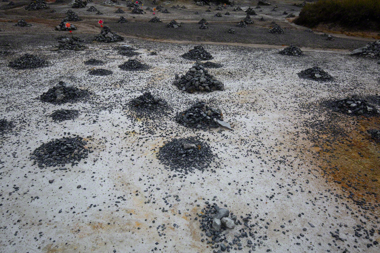 Mounds of stones line the tract known as Sai no Kawara, a reference to the riverbank separating the two worlds in Japanese Buddhist lore. The cairns are placed there on behalf of children who died before they could perform their sacred filial duty to their parents. (© Ōnishi Naruaki)