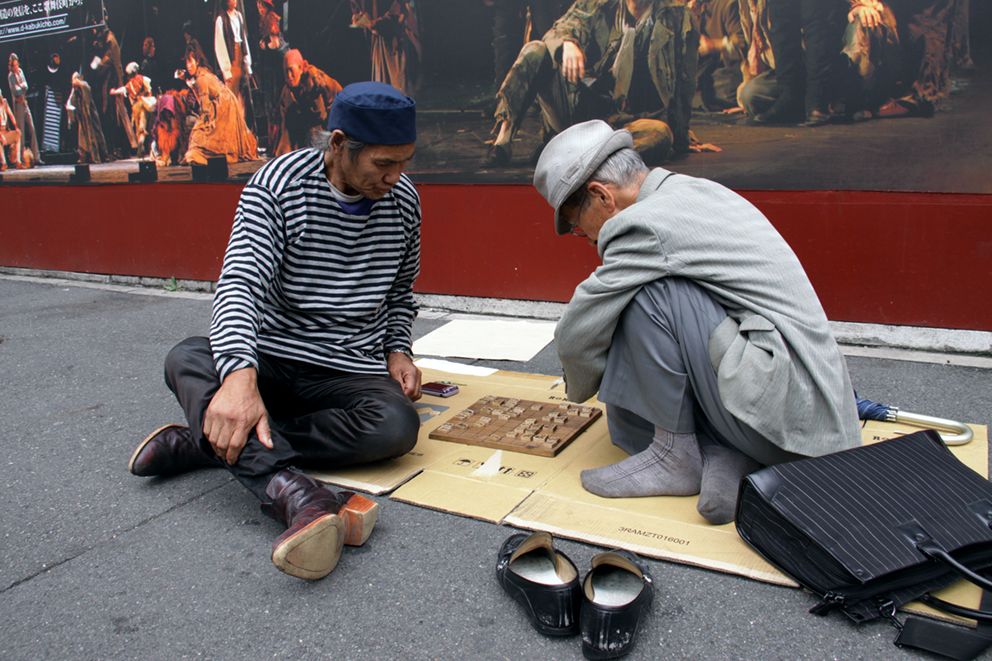 From Baggage. The suited man (right), previously homeless, accepted support and moved into a shelter a month ago. He still comes here each day to play shōgi with his friend. (© Yang Seung-Woo)