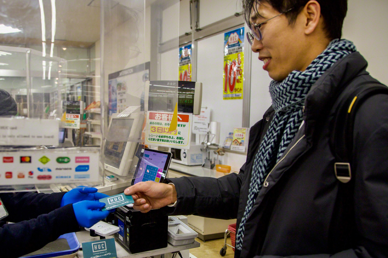 Kim effectuant un achat avec une carte HUC